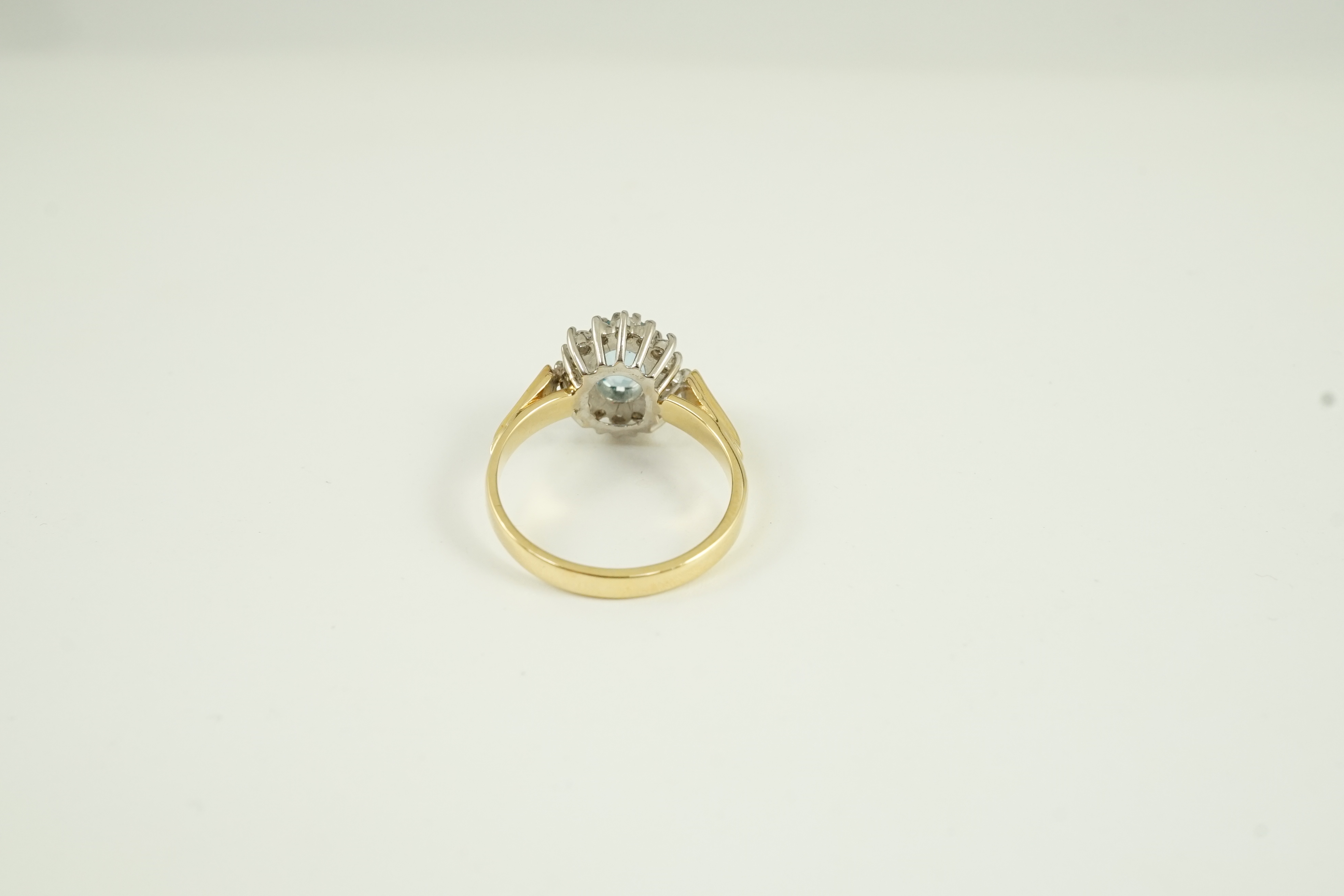 A modern 18ct gold aquamarine and diamond set oval cluster ring, size K/L, gross weight 3.8 grams.